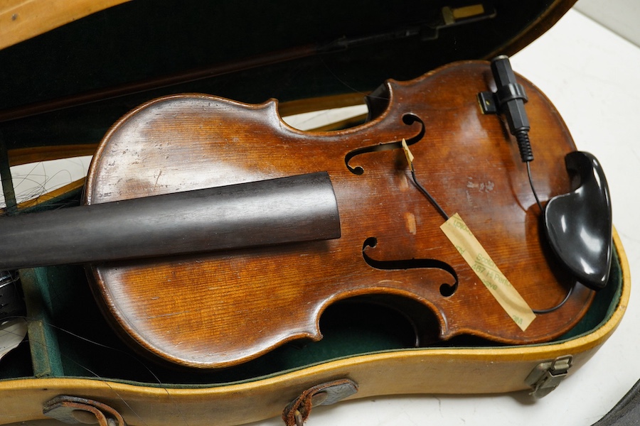 Four cased violins; an early 20th century violin, body 36cm, fitted with a microphone pick up taking a quarter inch jack plug, an early 20th century half size violin, body 32cm, and two student violins. Condition - poor